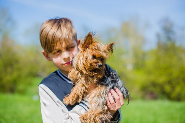 公園で彼の犬とポーズをとっている少年