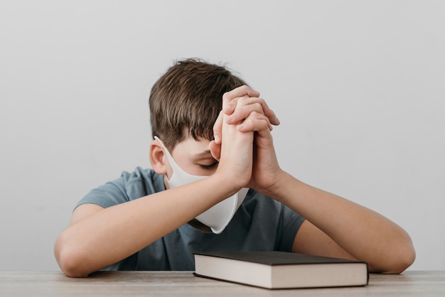 Boy praying while wearing a medical mask