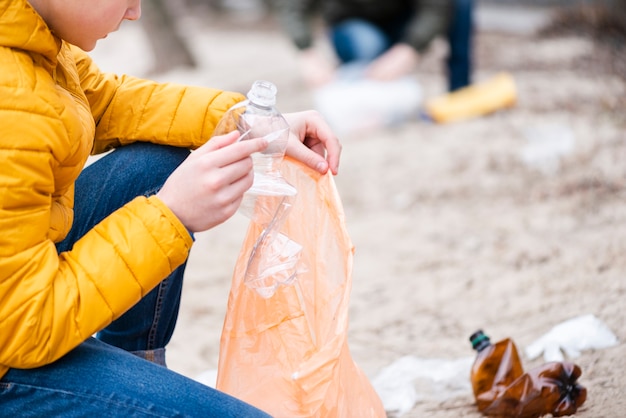 Foto gratuita ragazzo che mette la bottiglia di plastica in borsa