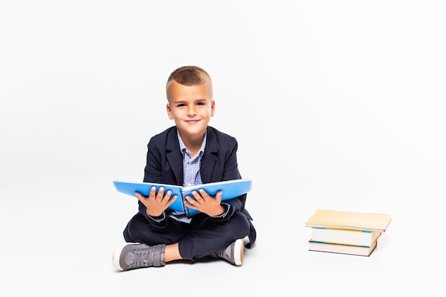 Boy read book sitting on the floor on a white wall