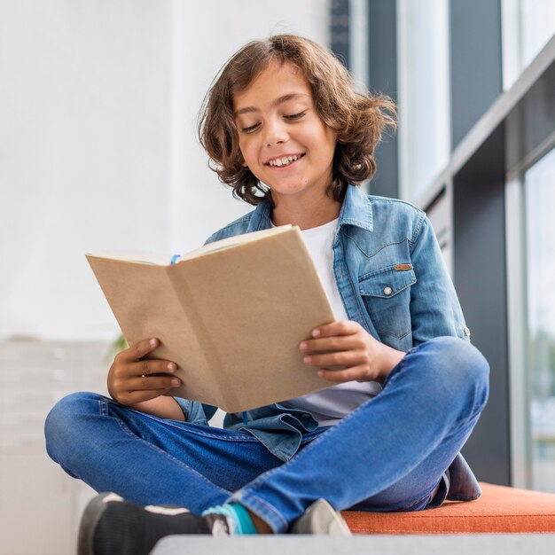 Boy reading from a book next to a window