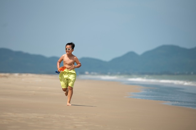 Boy running on beach full shot