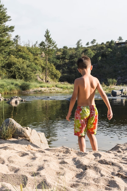 水の近くの砂の海岸の上の少年