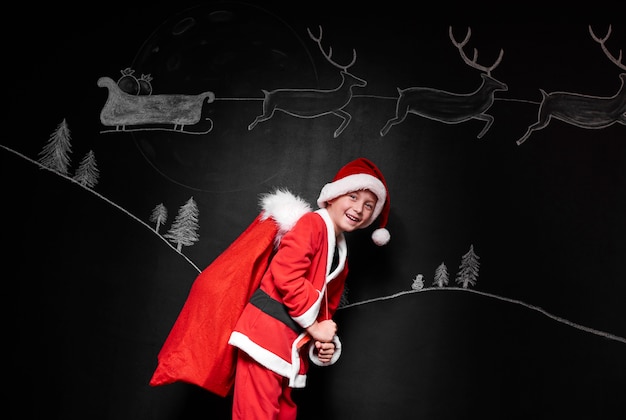 Boy in santa claus costume carrying a sack of gifts