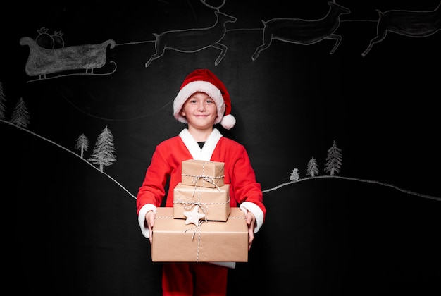 Boy in santa claus costume giving pile of gifts