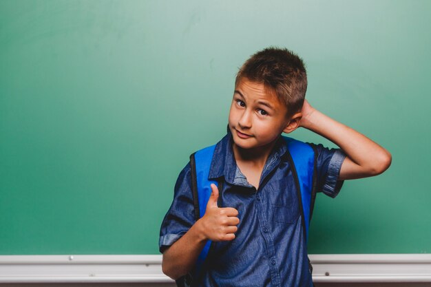 Boy scratching head and gesturing thumb up