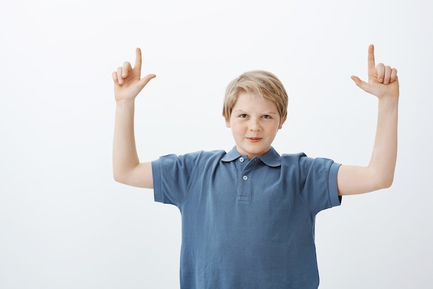 Free photo boy sharing interesting copy space with us. intriguing good-looking young make kid with blond hair