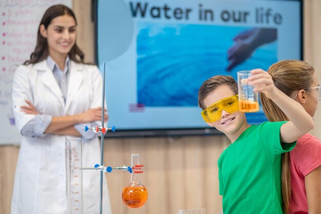 Boy showing glass standing with back to girl