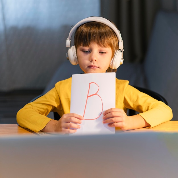 Boy showing a paper with the letter b on virtual courses