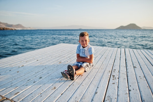 Boy sit at Turkey resort on pier against Mediterranean sea