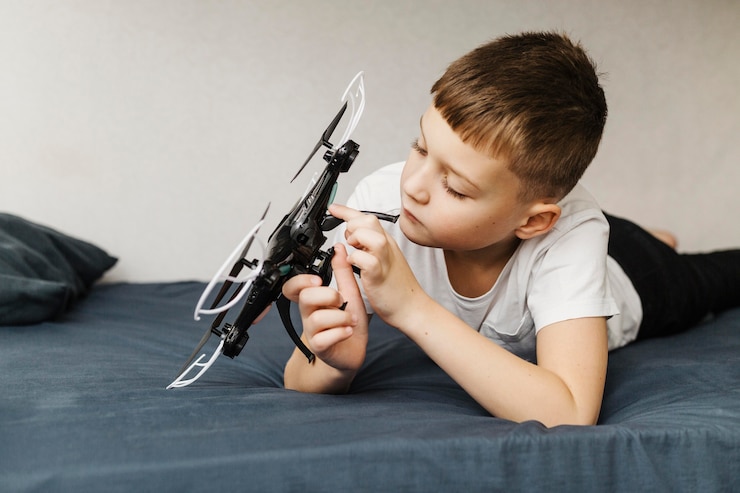 Free Photo boy sitting in the bed and playing with drone