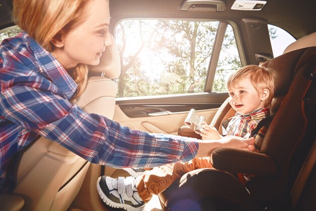 眠っている赤ちゃんは車の座席に乗ります 車で幸せな赤ちゃんに乗る 子供の安全 チャイルドシートの車で寝ているかわいい男の子 プレミアム写真