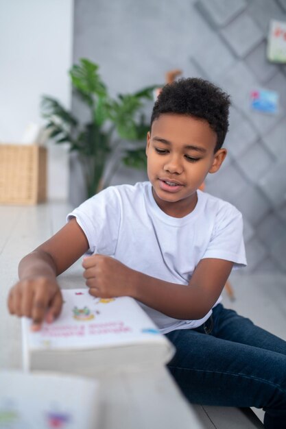 Boy sitting looking at book touching with finger