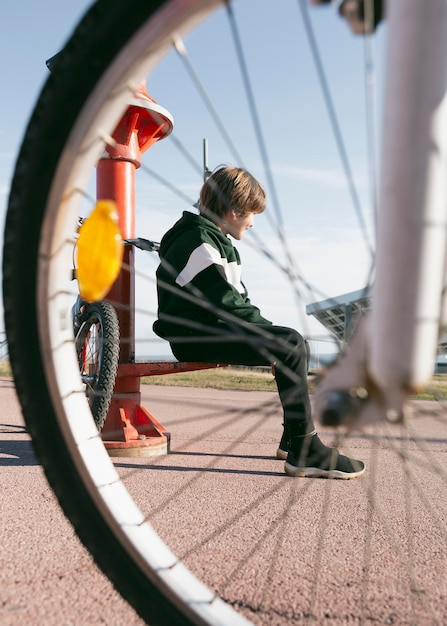 自転車で屋外の望遠鏡の隣に座っている少年