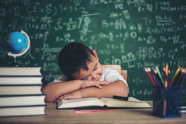 Boy sleeping on the books in the classroom.