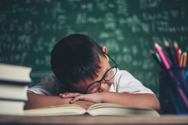 Boy sleeping on the books in the classroom.