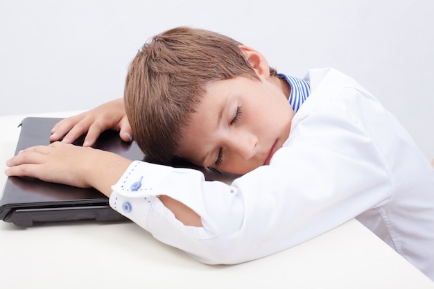 Free photo boy sleeping while using his laptop computer