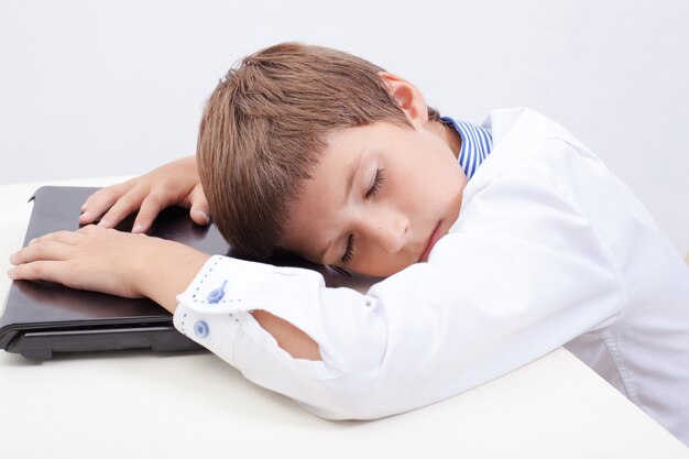 그의 노트북 컴퓨터를 사용하는 동안 자고있는 소년