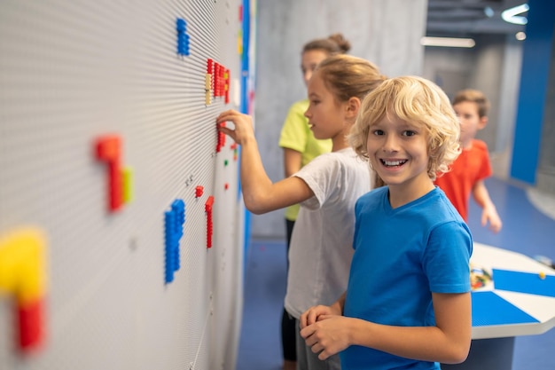 Boy smiling at camera playing lego with friends