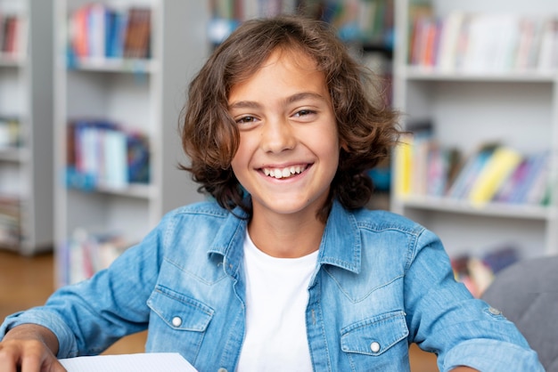 Foto gratuita ragazzo che sorride mentre era seduto in biblioteca