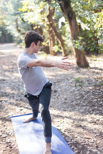 Foto gratuita ragazzo in abbigliamento sportivo facendo stretching nel parco