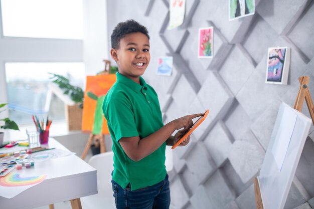 Boy standing near drawing easel looking at camera