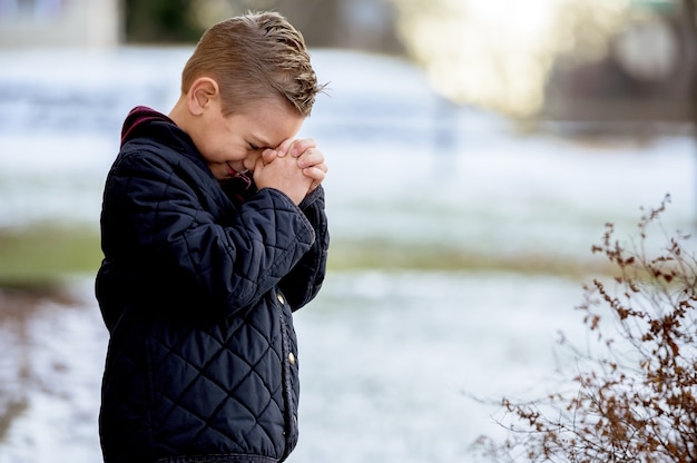 Free photo boy standing with closed eyes and praying