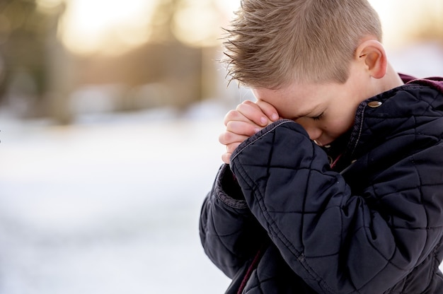 Free photo boy standing with closed eyes and praying