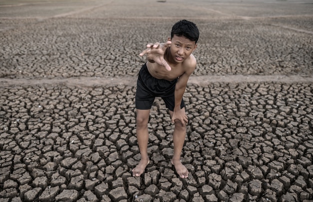 Мальчик стоял согнутый на коленях и сделал знак, чтобы попросить дождя, глобального потепления и водного кризиса.