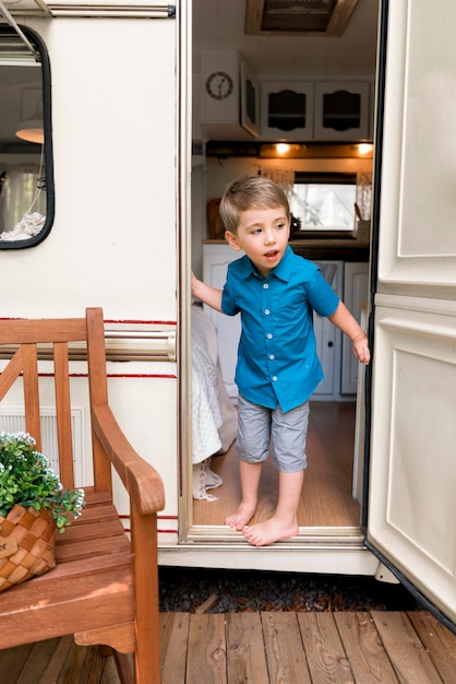 Free photo boy taking a look behind his caravan's door