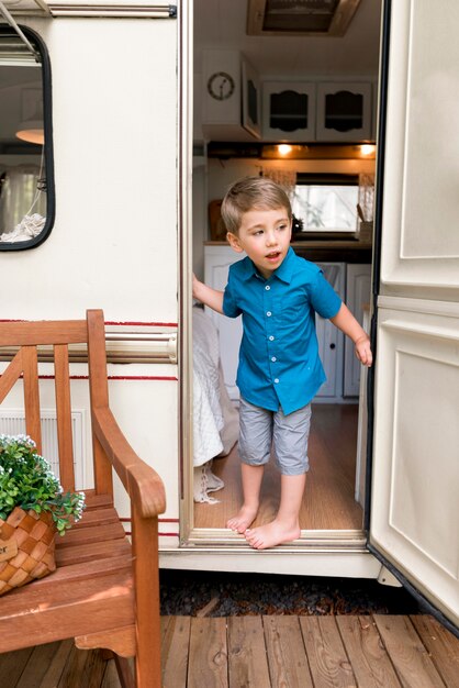 Boy taking a look behind his caravan's door