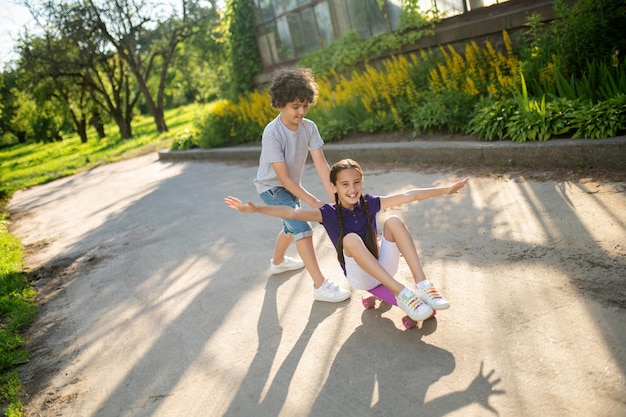 Ragazzo che insegna a una ragazza come fare skateboard