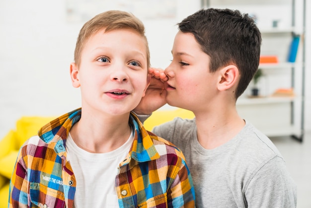 Free photo boy telling secret to friend