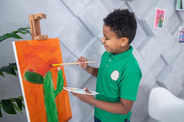 Boy touching drawing on easel with brush
