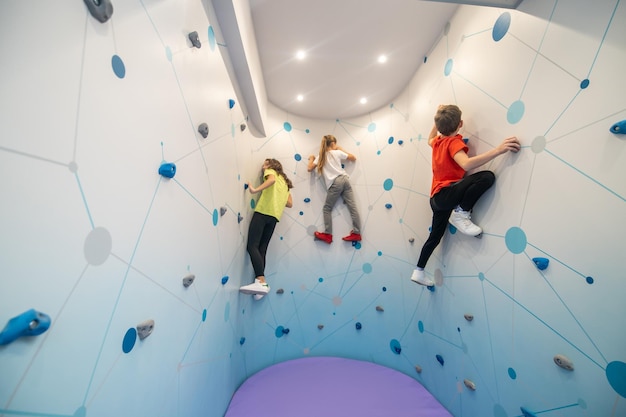 Boy and two girls climbing wall indoors