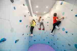 Free photo boy and two girls climbing wall indoors