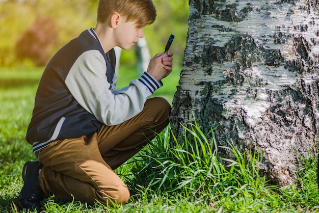 Ragazzo che usa la sua lente di ingrandimento nel parco