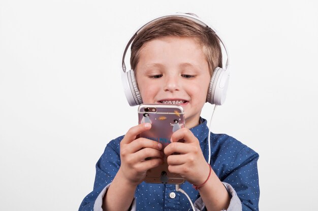 Мальчик использует смартфон и слушает музыку