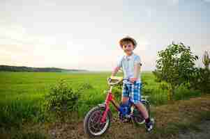 Foto gratuita il ragazzo indossa il cappello nei momenti felici dei bambini in bicicletta