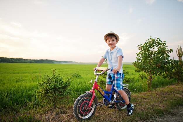 少年は自転車の幸せな子供たちの瞬間に帽子をかぶる