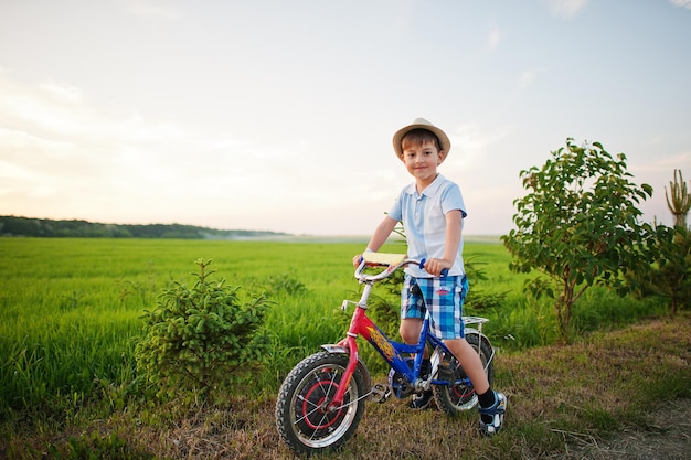 少年は自転車の幸せな子供たちの瞬間に帽子をかぶる