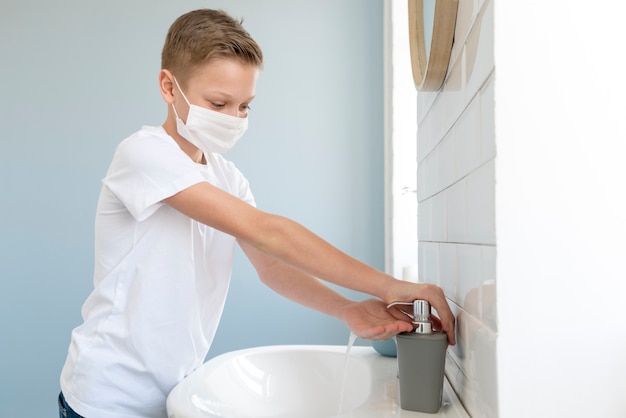医療用マスクを着用し、手を洗う少年