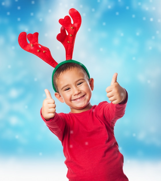 Boy wearing reindeer horns with christmas background