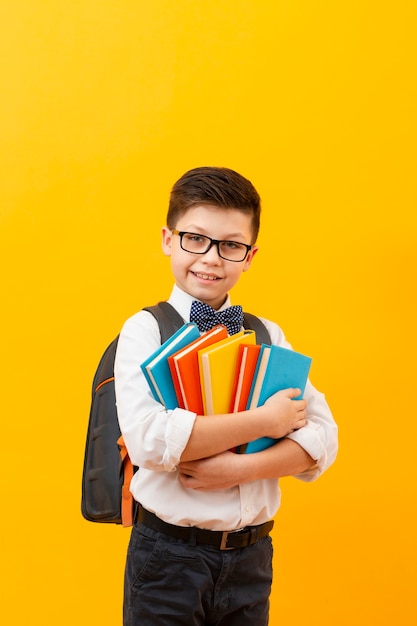 Boy with backpack holding stack of books