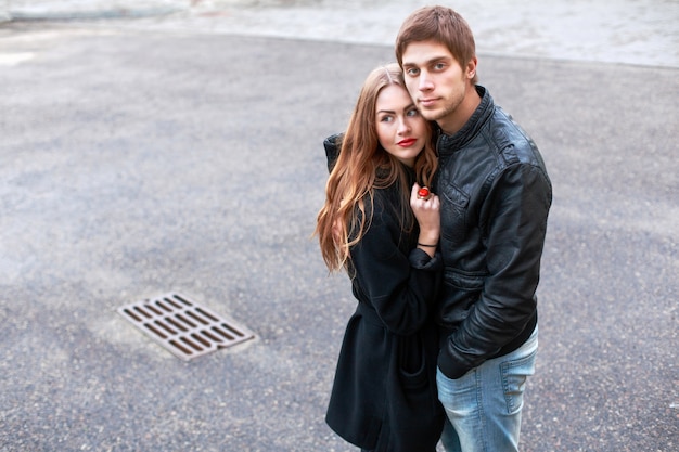 Boy with black leather jacket hugging his pretty girlfriend