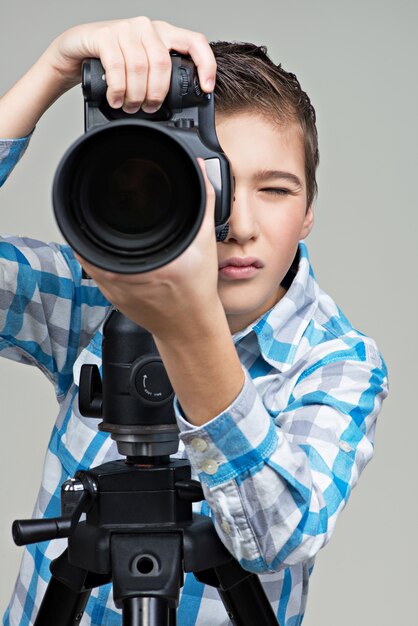 Boy with camera taking pictures. Boy  with dslr camera on the tripod.