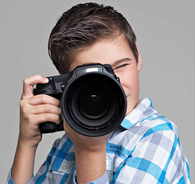 デジタル一眼レフカメラ撮影の少年。写真を撮るカメラを持つ10代の少年。