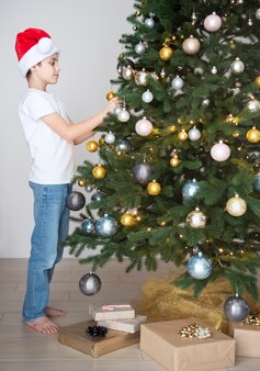 Boy with gifts plays near the christmas tree. living room interior with christmas tree and decorations. new year. gift giving.