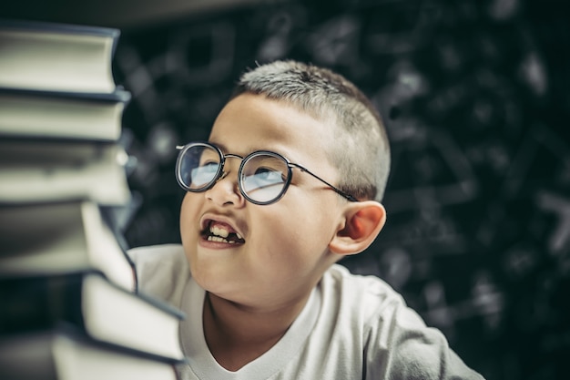 Мальчик в очках сидит в классе и считает книги