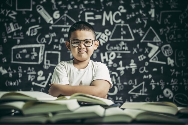 Мальчик в очках сидит в классе и читает